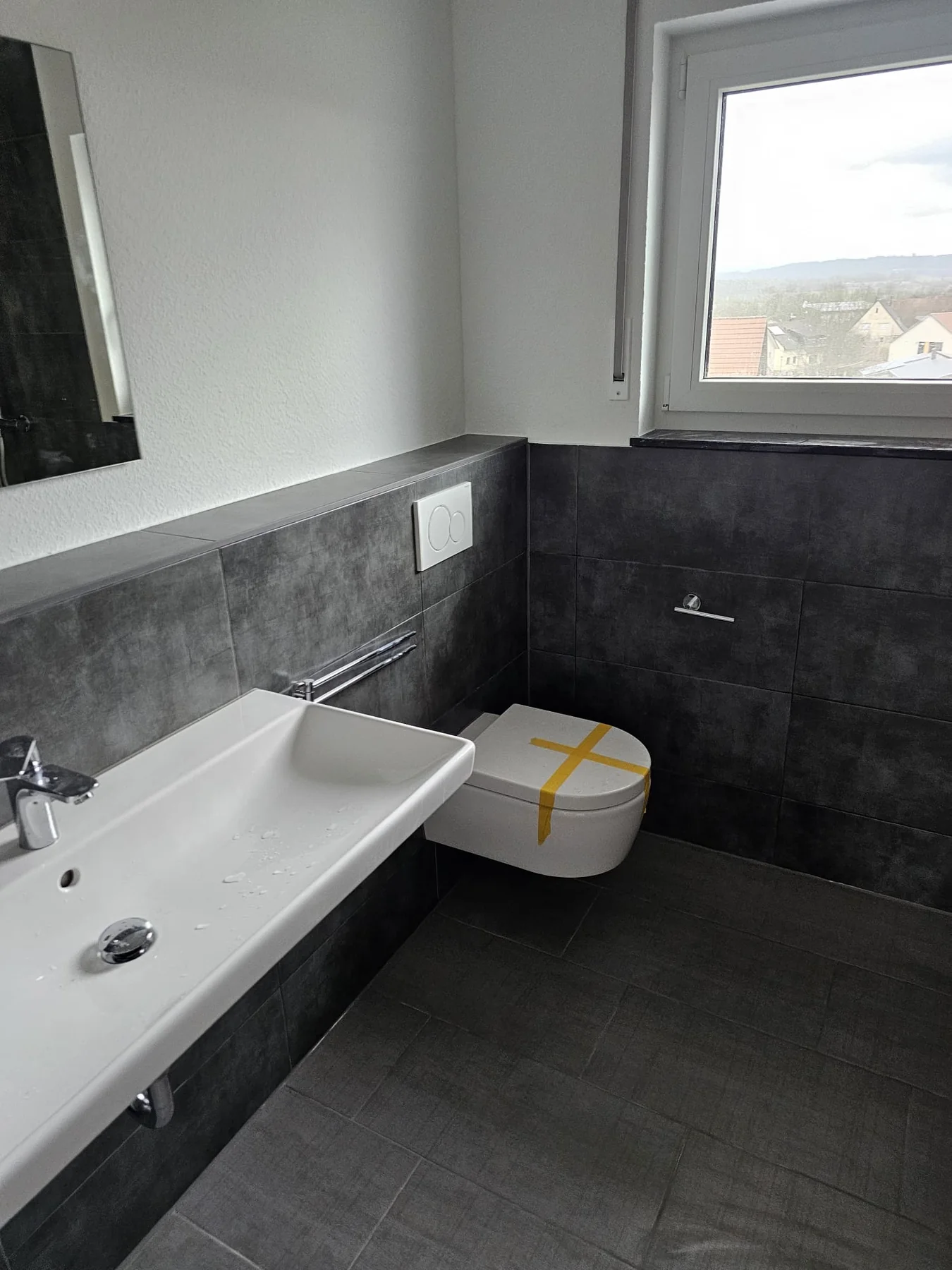 Modern gefliestes Badezimmer mit dunklen Wand- und Bodenfliesen