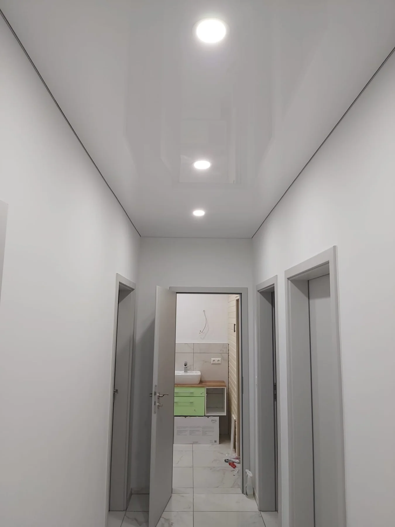 Moderne helle Spanndecke mit integrierter Beleuchtung in einem Wohnflur